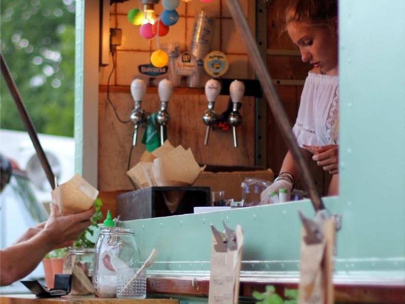 a food truck operator is shown preparing an order for a customer
