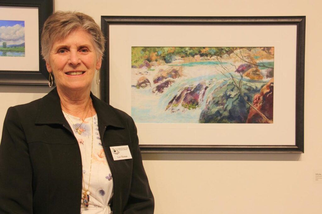artist stands alongside her painting