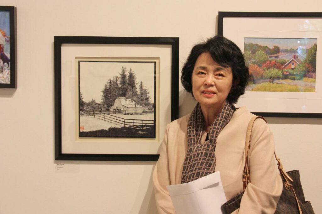 artist stands alongside her painting